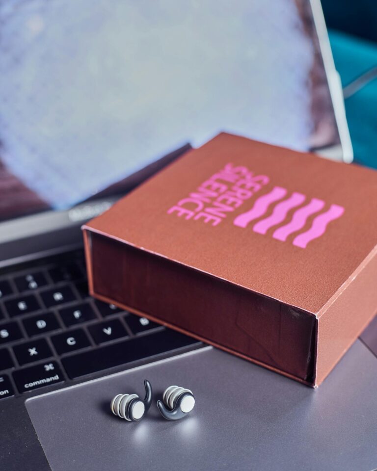 A laptop with a box of earphones on it